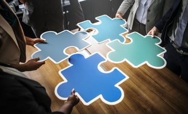 młodzi ludzie trzymają puzzle nad stołem