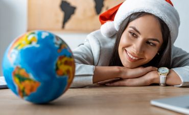 kobieta w czapce Mikołaja patrzy na globus