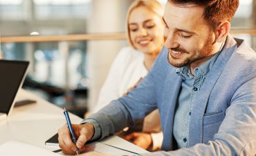 młodzi ludzie podpisują umowę