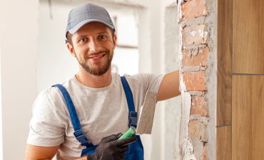 uśmiechnięty murarz w budowanym domu