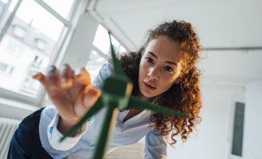 młoda kobieta dotyka makiety wiatraka