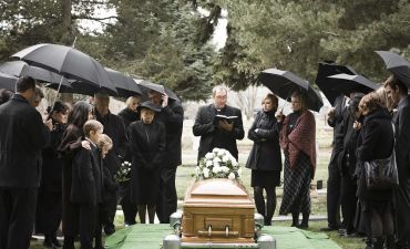 pogrzeb i żałobnicy stojący wokół trumny na cmentarzu