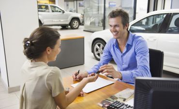 zadowolony mężczyzna podpisuje umowę najmu samochodu