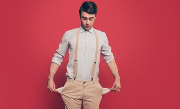 młody mężczyzna pokazuje puste kieszenie w spodniach