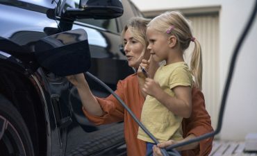 kobieta z dzieckiem ładuje samochód elektryczny