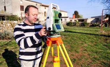 geodeta wykonuje pomiar działki za pomocą specjalistycznego sprzętu