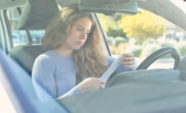 młoda kobieta czytające wezwanie do zapłaty kary za brak OC