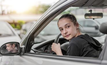 młody kierowca prowadzący samochód z zielonym listkiem