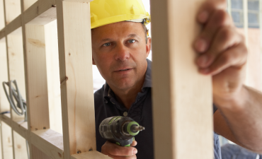 budowlaniec w kasku z pracuje z wkrętarką