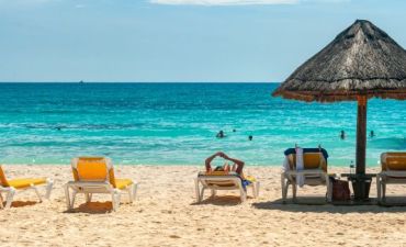 widok na plażę z leżakami i parasolem nad lazurową wodą na Zakhyntos
