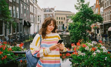 Kobieta stojąca w Rotterdamie wiosną i korzystająca ze smartfona