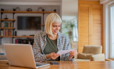 Uśmiechnięta kobieta przy biurku, przed komputerem.