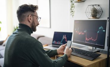 mężczyzna obserwuje notowanie giełdy na ekranie monitora