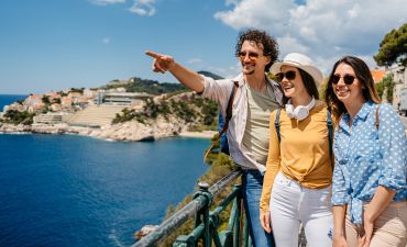 cztery osoby spacerują na świeżym powietrzu, podziwiając widok na skaliste wybrzeże i morze.