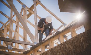 pracownik budowlany na drewnianej konstrukcji domu