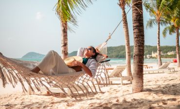 kobieta na wakacjach we wrześniu, odpoczywająca w hamaku, w tle plaża, morze i palmy