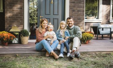 Kobieta, mężczyzna i dwójka dzieci siedzą przed domem