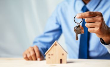 mężczyzna w błękitnej koszuli trzymający klucze do domu