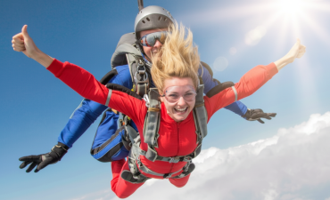 kobieta w czerwonym stroju, skacząca ze spadochronem