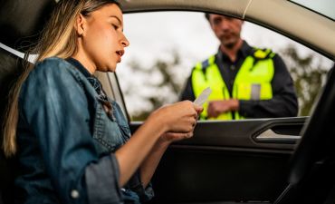 Kobieta w samochodzie i policjant sprawdzający jej dokumenty