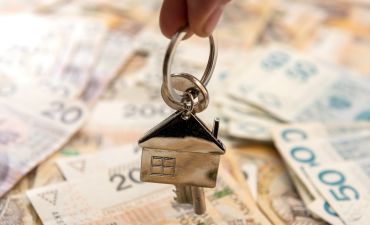 Brelok w kształcie domu na tle pieniędzy