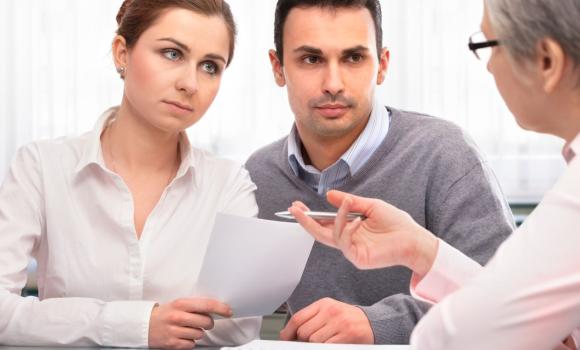 Młoda para podczas rozmowy z doradcą w biurze podróży, analizująca dokumenty i ofertę wycieczki. Opis rozszerzony (na stron